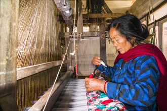 A woman is working on an old traditional loom