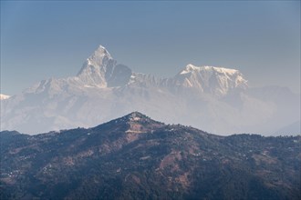 Summits of Annapurna III and Machapuchare in the haze behind the Sarangkot mountain ridge