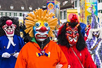 Many different groups of masked people walking through the streets of Basel
