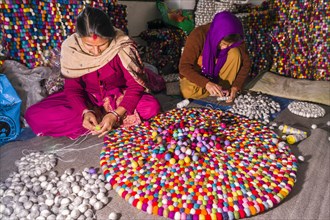 Women are producing a carpet from felt balls