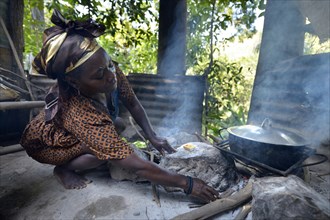 Woman is cooking on an open fire in a simple kitchen