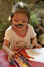Girl with face painted as a cat drawing at a children's festival