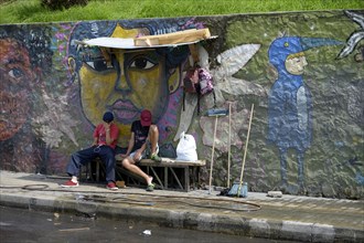 Young gang members sitting in front of graffiti wall