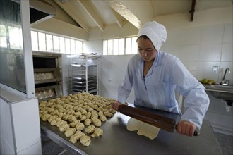 Teen rolling out dough in the bakery of a social project