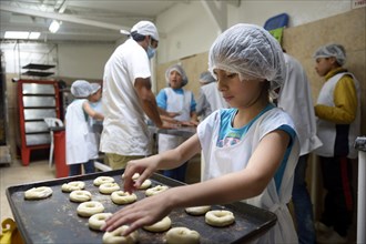 Girl placing raw dough rings onto tray