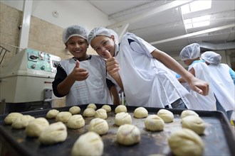 Two boys behind baking tray with raw dough