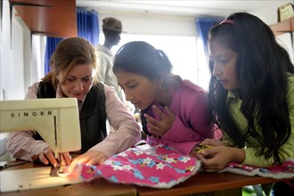 Girls and teacher using sewing machine