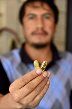 Man holding two pieces of gold in shop
