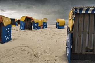 Abandoned beach chairs in front of dark clouds
