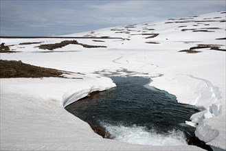 Partially frozen and snow-covered Lake Heidarvatn