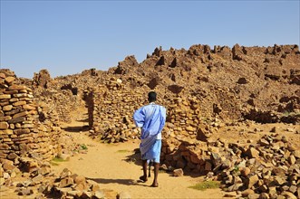 Man in blue boubou among the ruins of the fortified trading post or Ksar