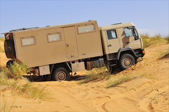 Truck with camping space is stuck in sand