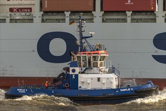 Tugboat next to container ship on the river Elbe