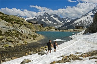 Tourists in snowfield at Lac Blanc mountain lake in Aiguilles Rouges National Nature Reserve
