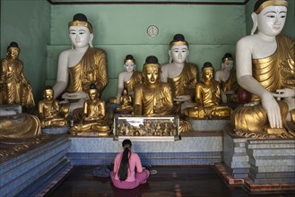 Local woman meditating in front of Buddha statues