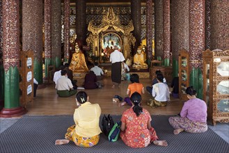 People meditating in front of Buddha statues