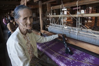 Old local woman weaving fabric from lotus flower silk