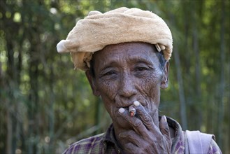 Old local man with headgear smoking a cigar