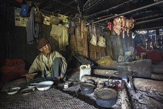 Local man from the tribe of the Loi having a meal in the cooking area in a longhouse in the mountain village Wan Sen