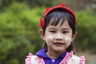 Local girl with a red cap and Thanaka paste on her face