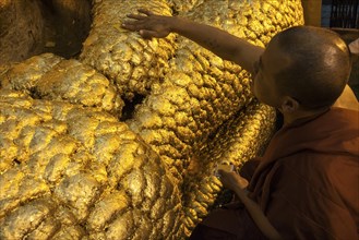 A monk sticking leaf gold to the Mahamuni Buddha statue