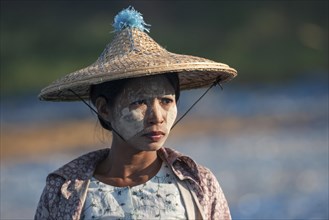 Local woman with straw hat and Thanaka paste on her face