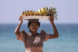 Native woman with a bowl of bananas on her head and Thanaka paste on her face