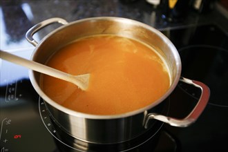Soup in pot with wooden spoon