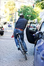 Cyclist in the city dodging a car door being opened
