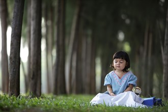 Little girl meditating in a pine forest