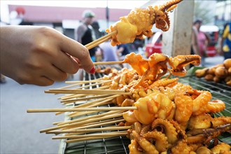 Hand holding a skewer with octopus
