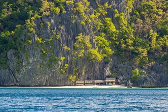 Small huts against dramatic karst cliffs on Coron Island