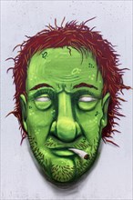 Portrait of a man with a green face smoking weed