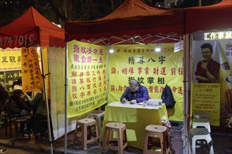 Chinese fortune tellers and palm readers in a lit tent