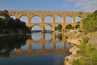 Roman aqueduct Pont du Gard reflected in the Gardon river