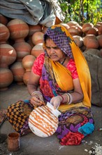 A woman painting pots and water jugs at a pottery stall in Jaipur
