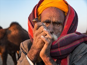 Elderly Rajasthani man with an turban smoking a hash pipe