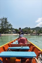 Local man steering longtail boat from rear