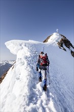 Mountaineer climbing in the snow on the Wildspitze on the summit ridge with snow cornice