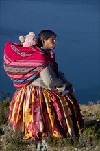 Indio woman with a young child on her back