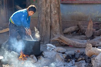 Schoolboy preparing breakfast on an open fire