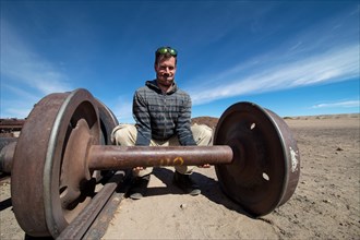 Young man lifting train axle like dumbbell