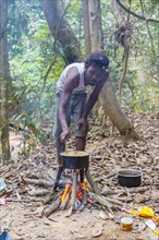 Man of the Orang Asil cooking food on a fire in the jungle