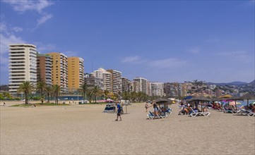 Deck chairs on the beach and skyscrapers behind at Playa de la Malagueta