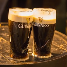 Beer glasses with Guinness beer on wooden barrel in the Irish Pub