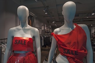 Two modern mannequins decorated for a closing sale