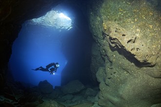 Diver with lamp in rocky cave
