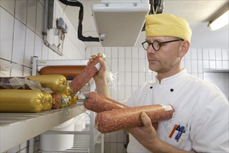 Cook with sausages in the fridge of a canteen kitchen