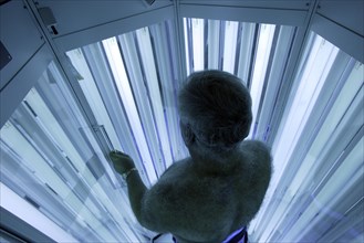 Man standing in an UV phototherapy cabin for UV light therapy at a dermatologist