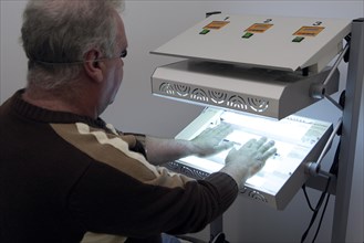 Patient has his hands in a phototherapy box for an irradiation treatment